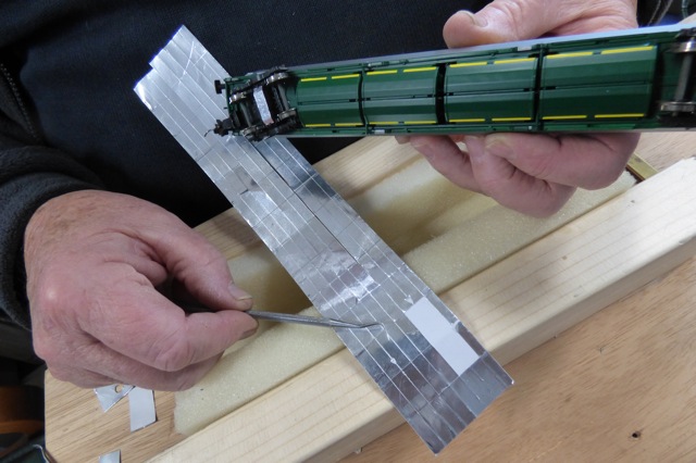 Aluminium Foil Tape on the bottom of a model train carriage - with tape slit to be fitted